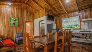 Un interior de madera con una mesa de comedor y sillas, un sofá y una zona de cocina.