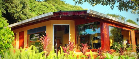 A building with a glass door and windows, surrounded by lush greenery.