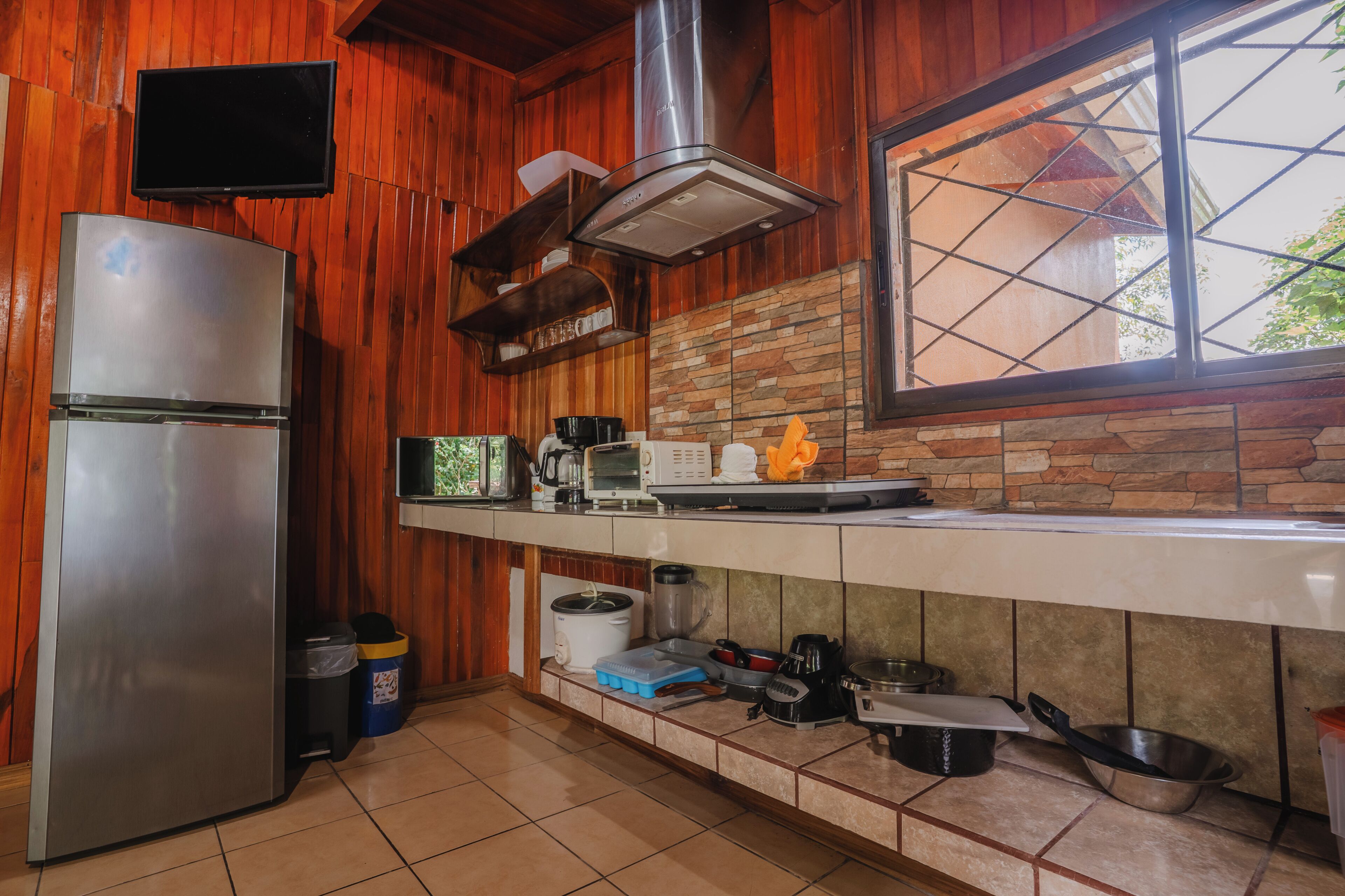 Una cocina con paredes de madera, un refrigerador de acero inoxidable, una estufa y una ventana con vistas.