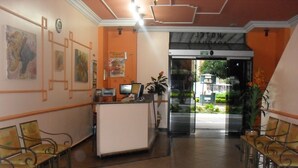 Un espace d’accueil comprenant un comptoir, des chaises et une porte vitrée donnant sur l’extérieur.