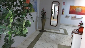 Un espace d’accueil agrémenté d’une plante en pot, d’un miroir et d’œuvres d’art accrochées aux murs.