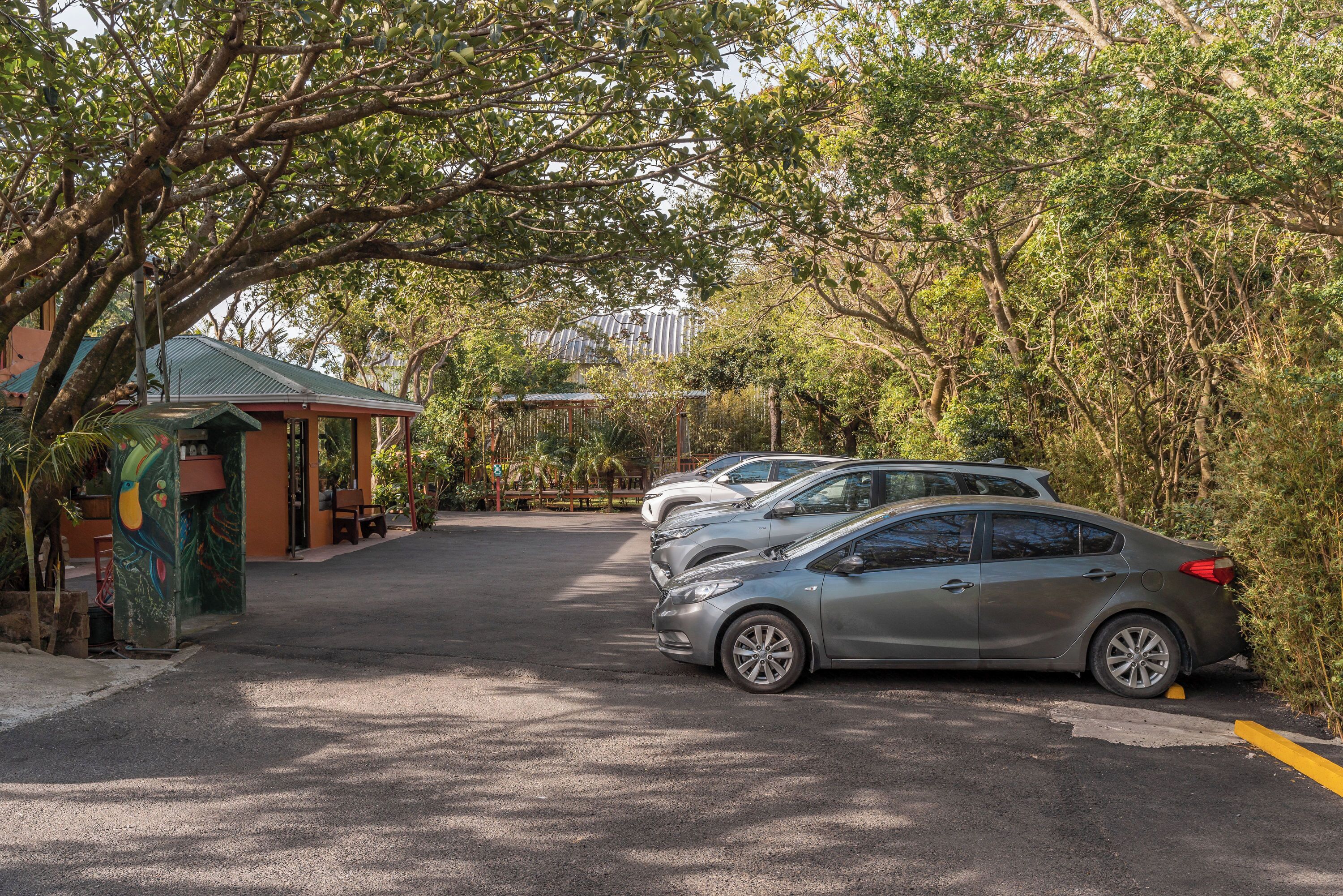 A parking area with cars and a building with a green roof.