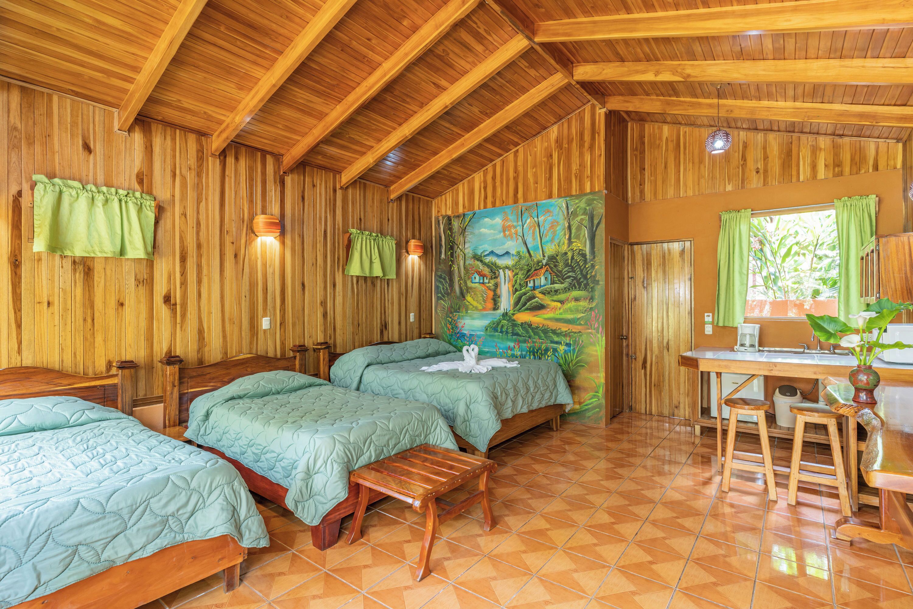 Une cabane en bois avec deux lits, un coin repas et un tableau accroché au mur.