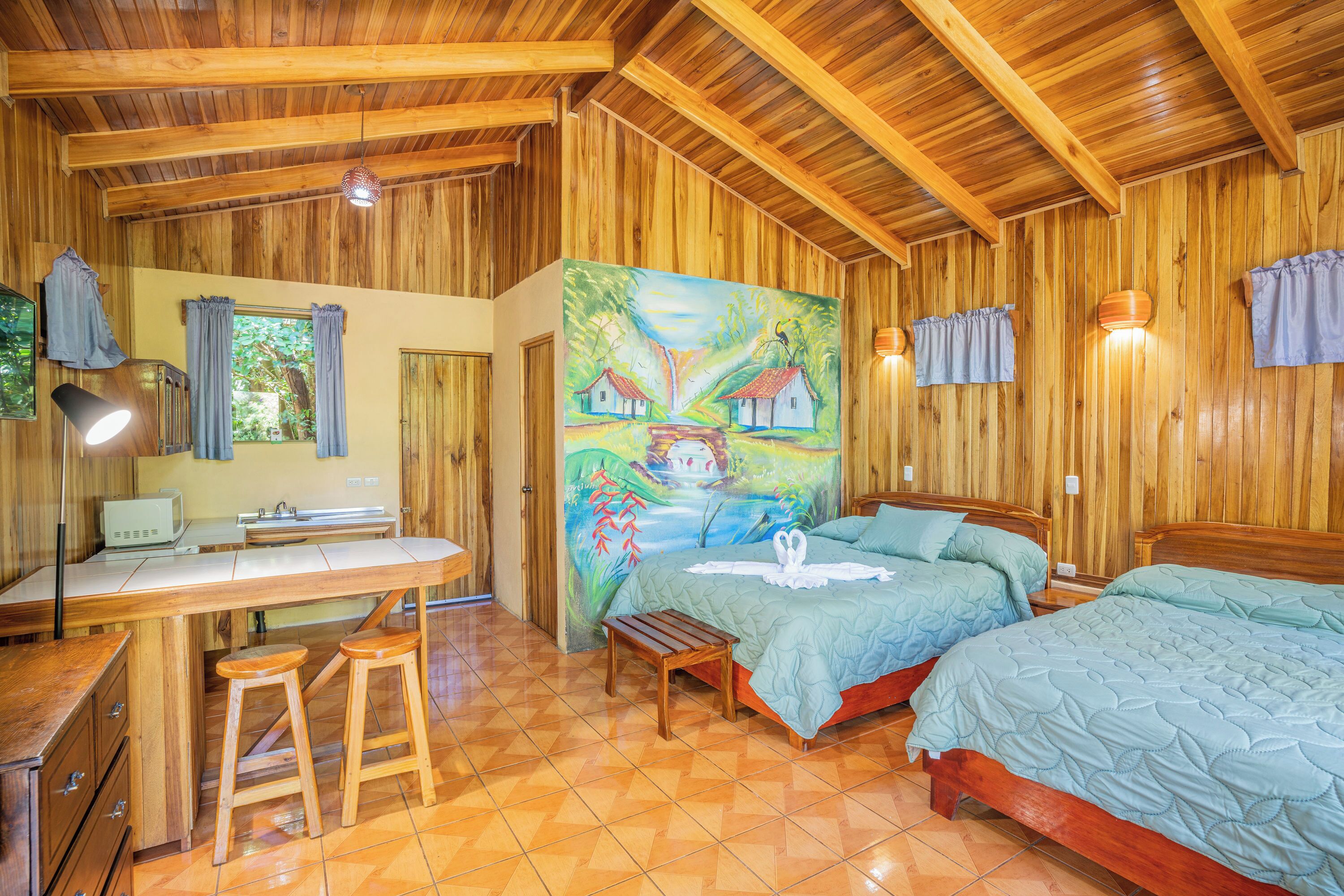 Habitación con decoración de madera, una cama, un escritorio y un cuadro de casas.