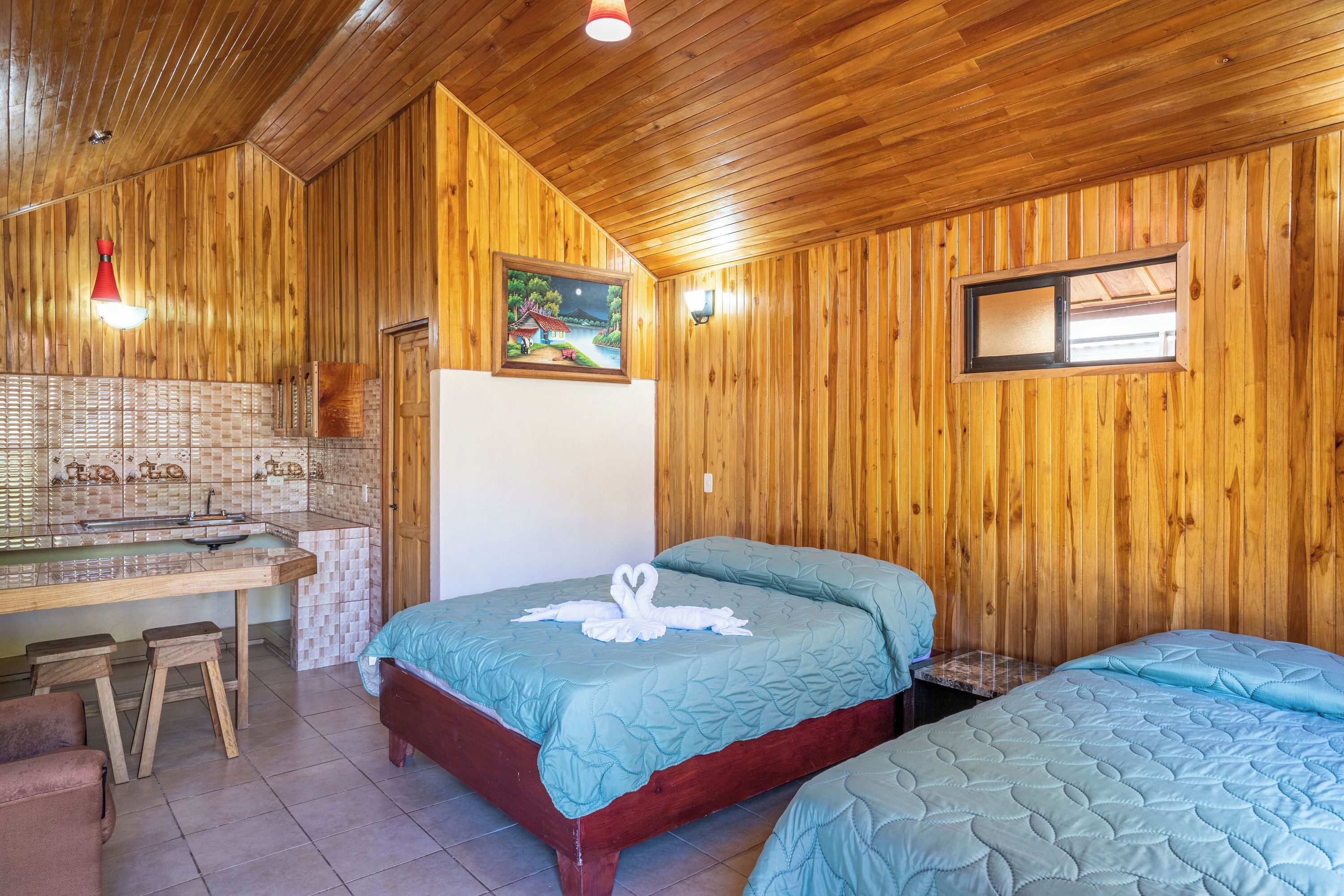 A wooden-paneled room with a bed, a small table, and a bench.