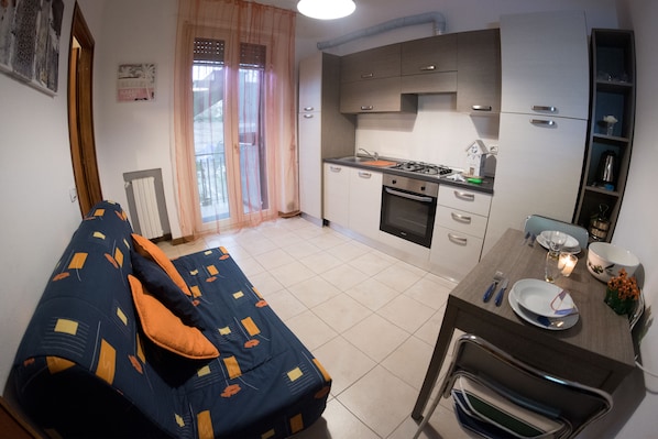 A compact living space with a sofa, dining table, and kitchenette. - Le Dimore del Sole (Cagliari)