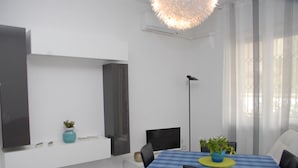 A modern meeting room with a blue table, black chairs, a potted plant, and a large pendant light. - Le Dimore del Sole (Cagliari)