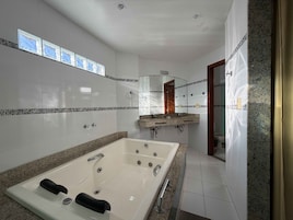 Un baño moderno con una bañera grande, un tocador con espejo y una zona de ducha.