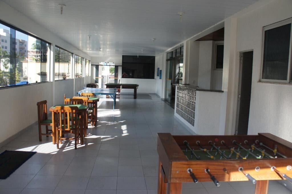 A room with a foosball table, a pool table, and several chairs.