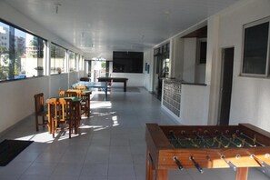 A room with a foosball table, a pool table, and several chairs.
