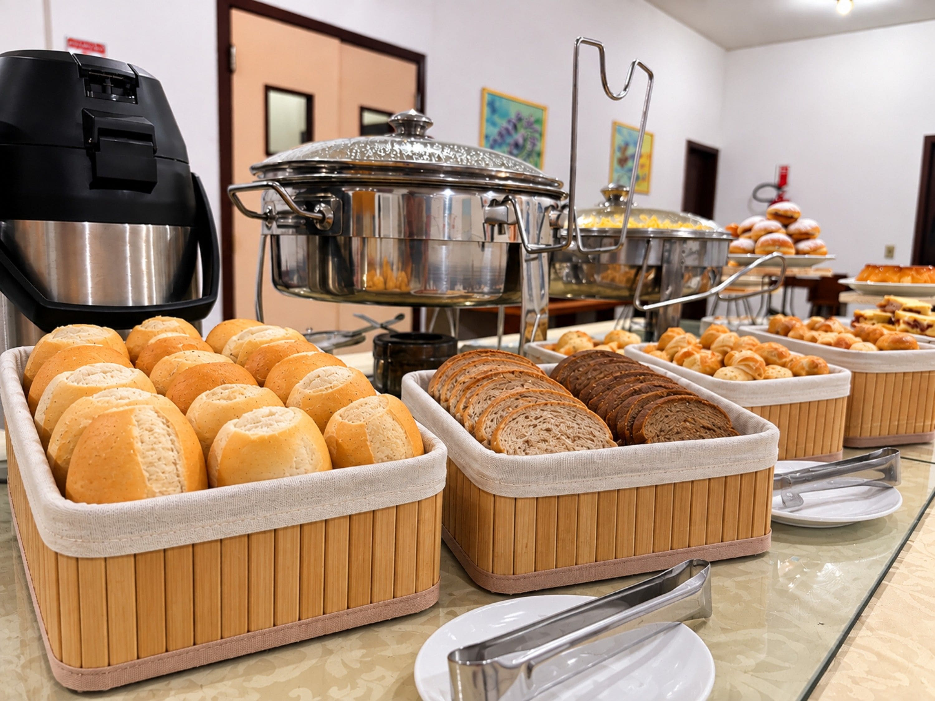 A buffet with various bread and pastries, a coffee machine, and a large pot on a stove.