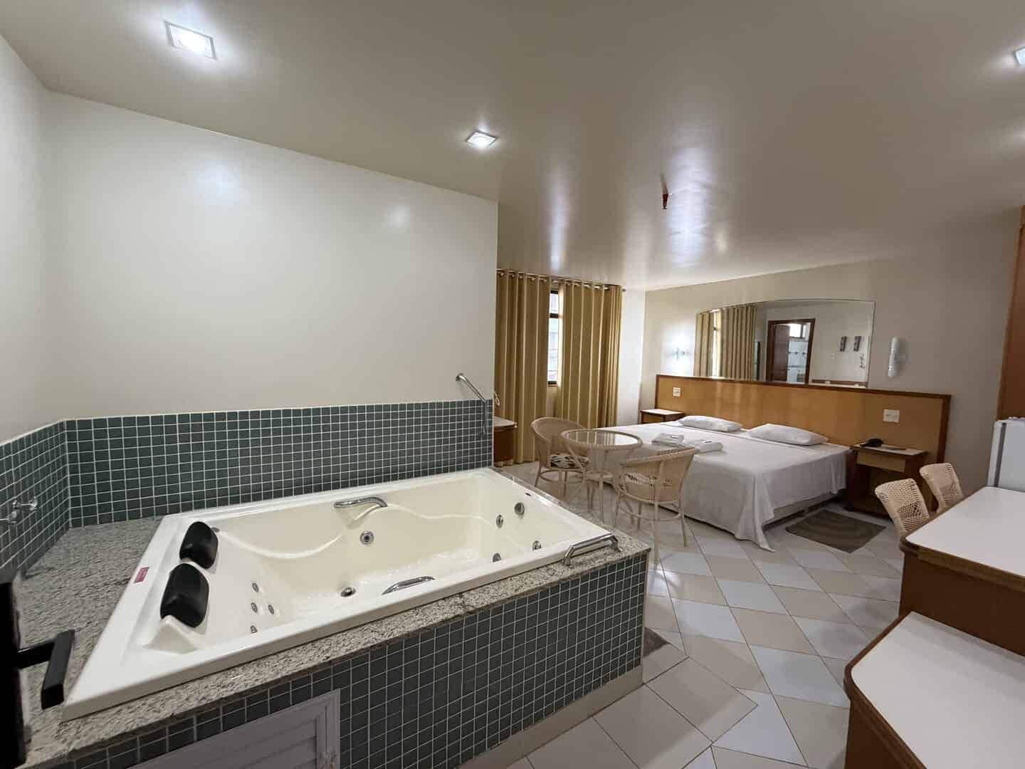 Une chambre d’hôtel avec une grande baignoire, un lit, un bureau et une chaise.