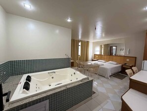 Habitación de hotel con una bañera grande, cama, escritorio y una silla.