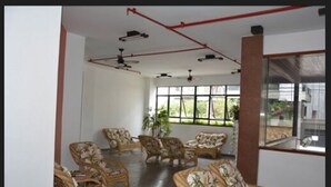 A spacious room with wicker furniture, large windows, and ceiling fans. - Joalpa Hotel Cabo Frio (Cabo Frio)