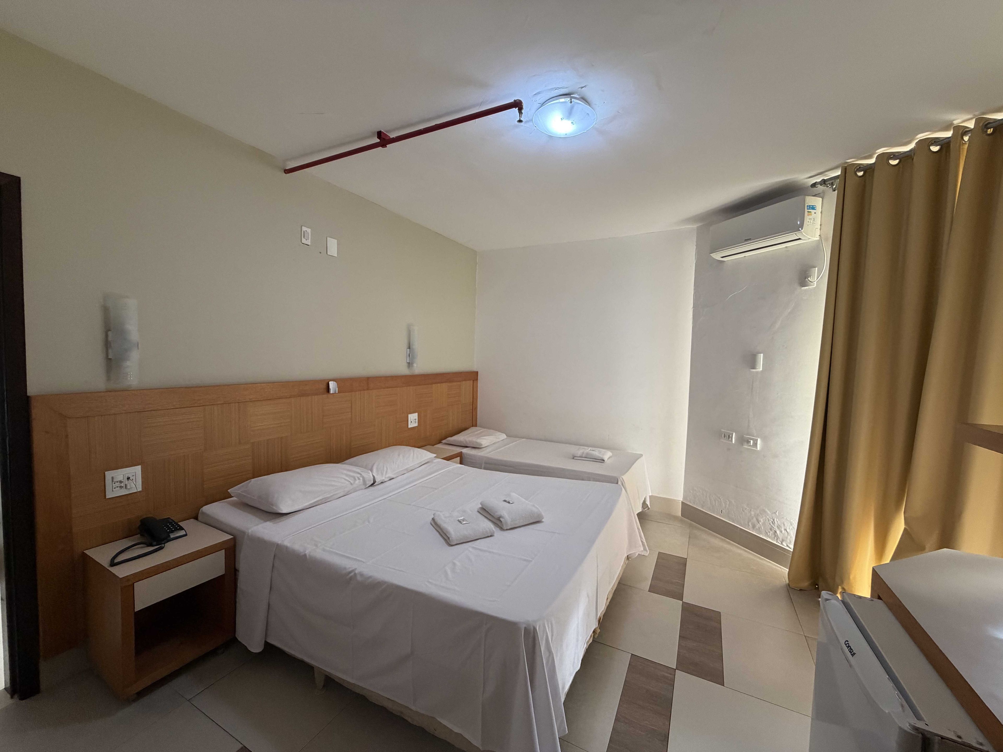 Ein Hotelzimmer mit einem großen Bett, Nachttischen, einem Telefon und einem Duschbereich.