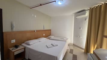 Ein Hotelzimmer mit einem großen Bett, Nachttischen, einem Telefon und einem Duschbereich.