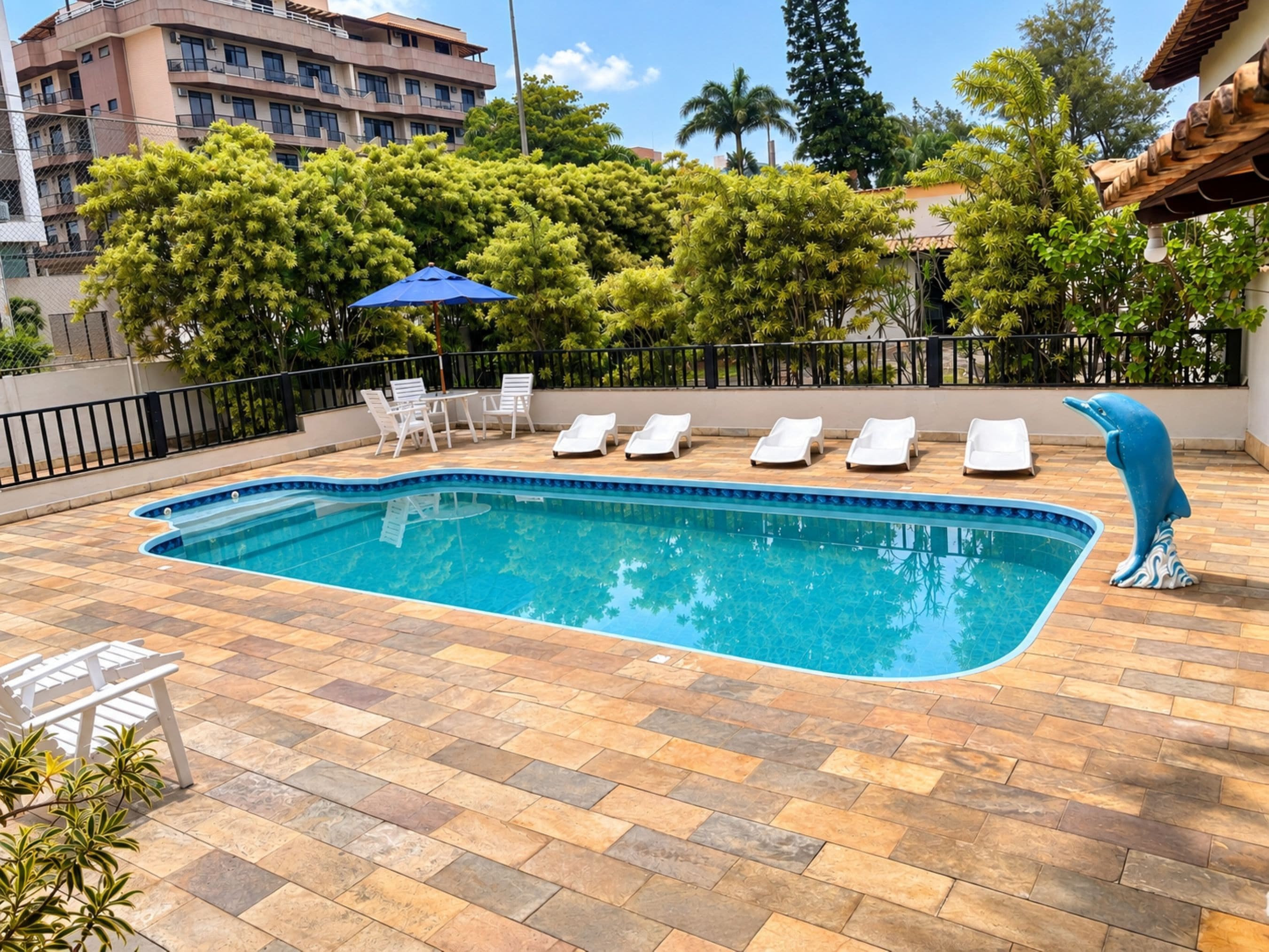 A swimming pool with lounge chairs and a dolphin statue.