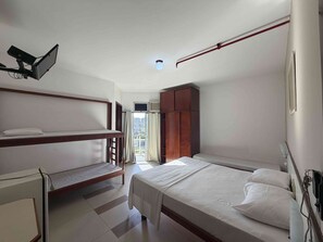 A bedroom with a bunk bed, a single bed, a wardrobe, and a window with curtains.
