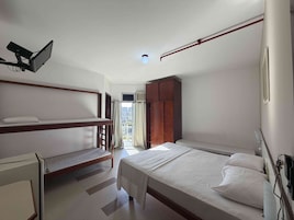 Un dormitorio con una litera, una cama individual, un armario y una ventana con cortinas.