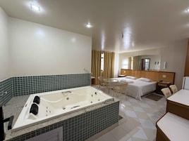 Una camera d'albergo con vasca, un letto, una scrivania e una sedia.