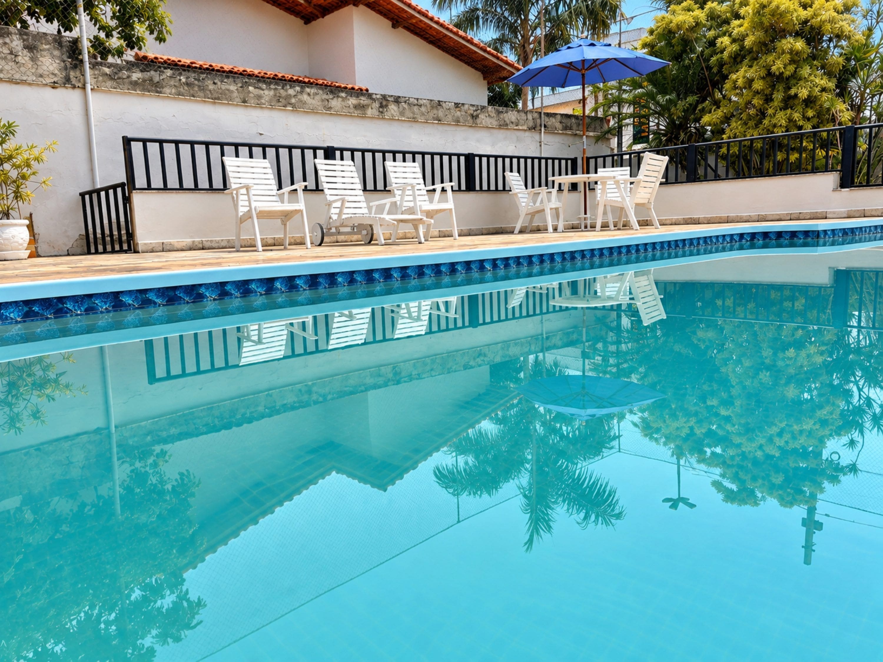 Una piscina con sillones de descanso y una sombrilla.