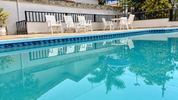 Una piscina con sillones de descanso y una sombrilla.