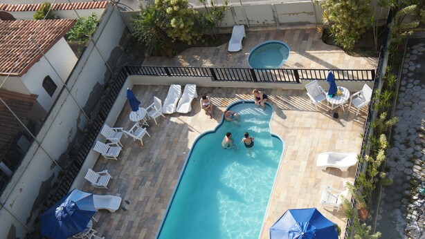 An aerial view of a swimming pool area with lounge chairs and umbrellas. - Joalpa Hotel Cabo Frio (Cabo Frio)
