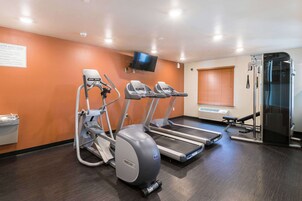 Academia com esteiras, elípticos e aparelho de musculação.