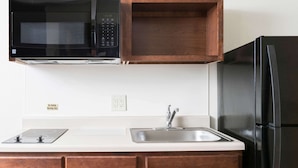 A kitchen with a microwave, a sink, and a refrigerator. - WoodSpring Suites Lafayette (Lafayette)