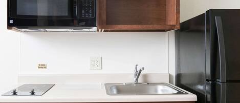 A kitchen with a microwave, a sink, and a refrigerator.