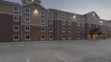 A hotel with a modern design, featuring a mix of brick and wood paneling, multiple windows, and a well-lit entrance.