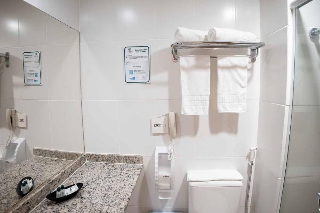 A modern bathroom with a granite countertop, a toilet, a glass shower enclosure, and a towel rack.
