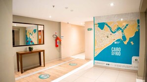 Un hall d’hôtel avec une console en bois, un extincteur, une carte accrochée au mur et un sol carrelé.