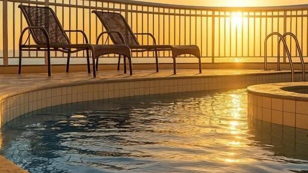 Un espace piscine avec des chaises longues et un ciel ensoleillé.