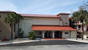 A building with a red roof, a central entrance, and a sign reading "TRICOVE". - Tricove Inn & Suites (Jacksonville)
