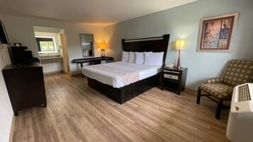 Une chambre d’hôtel avec un grand lit, un bureau, une chaise et une petite table avec une lampe.