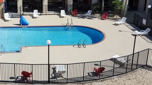 A swimming pool with a blue tiled interior, surrounded by a black metal fence. - Tricove Inn & Suites (Jacksonville)