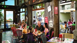 Un restaurante con terraza, vigas de madera y vistas a la calle.