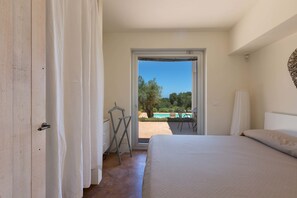A bedroom with a bed, a door, and a view of an outdoor swimming pool. - Villa Lisy (Carovigno)