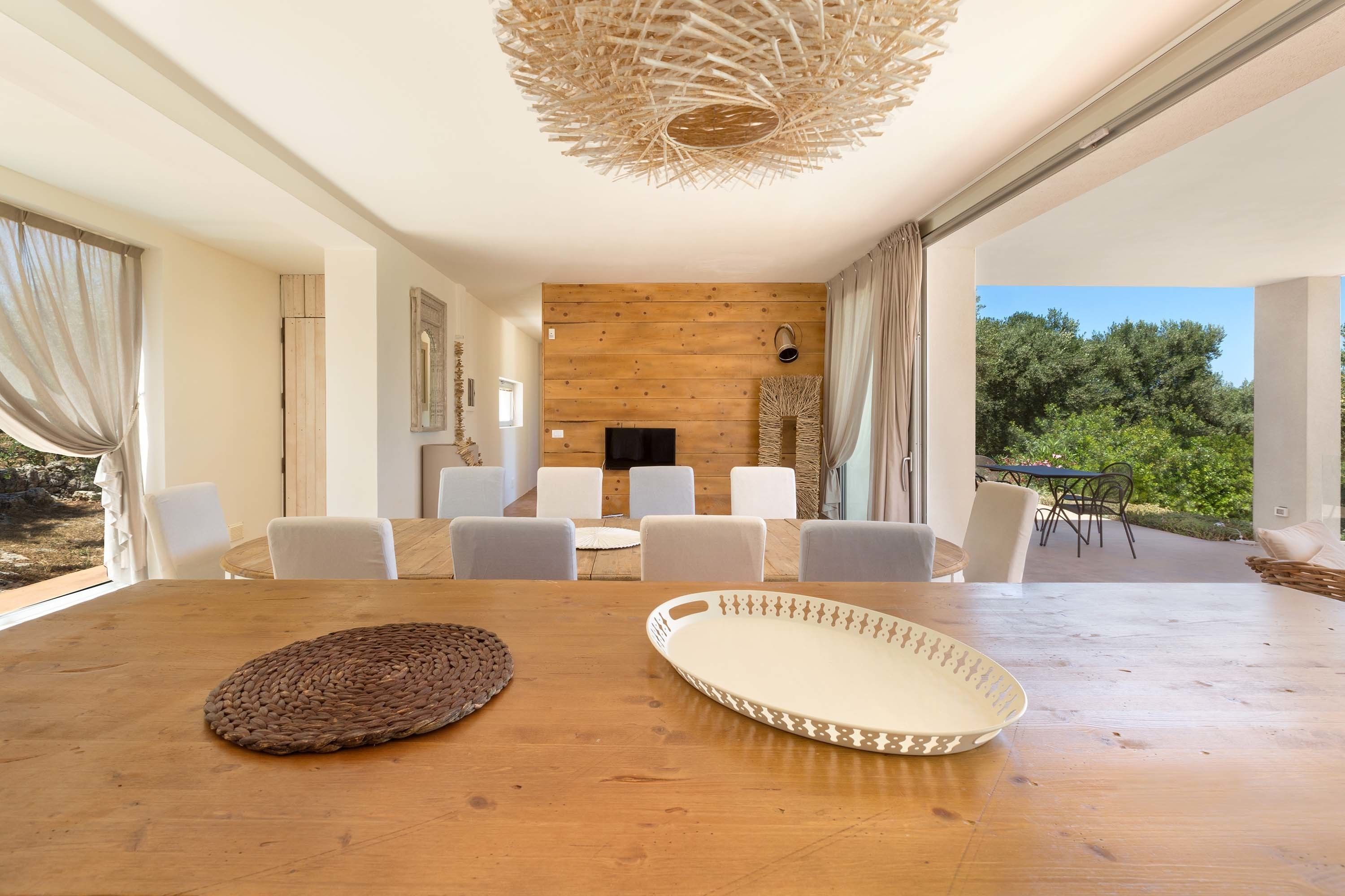 Un coin repas avec une table en bois, des chaises blanches et un set de table en fibres tressées.