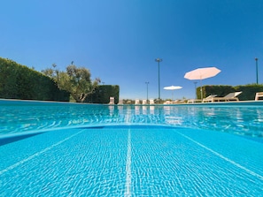 Piscine extérieure en saison, parasols, chaises longues