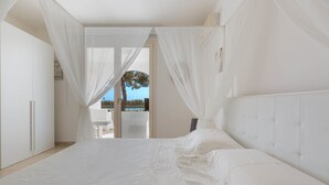 A bedroom with a large bed, sheer curtains, and a view of the outdoors. - Villa Maria Clara (Gagliano del Capo)