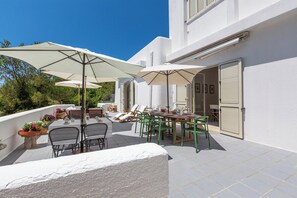 An outdoor patio with tables and chairs, umbrellas, and potted plants.