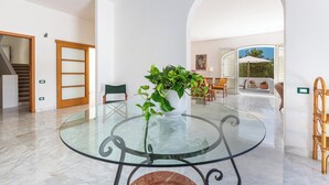Une pièce spacieuse avec une table en verre, une plante en pot et une vue sur un patio extérieur.