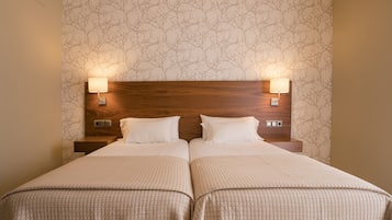 Ein Doppelbett mit zwei Nachttischen, an denen jeweils eine Wandlampe befestigt ist.