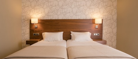 A double bed with two nightstands, each with a wall-mounted lamp.