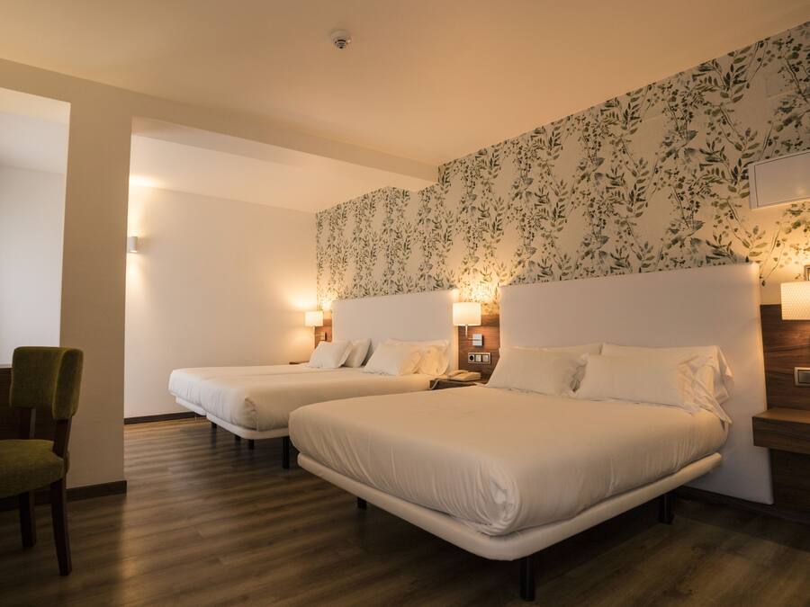 A hotel room with two beds, a desk, and a chair.