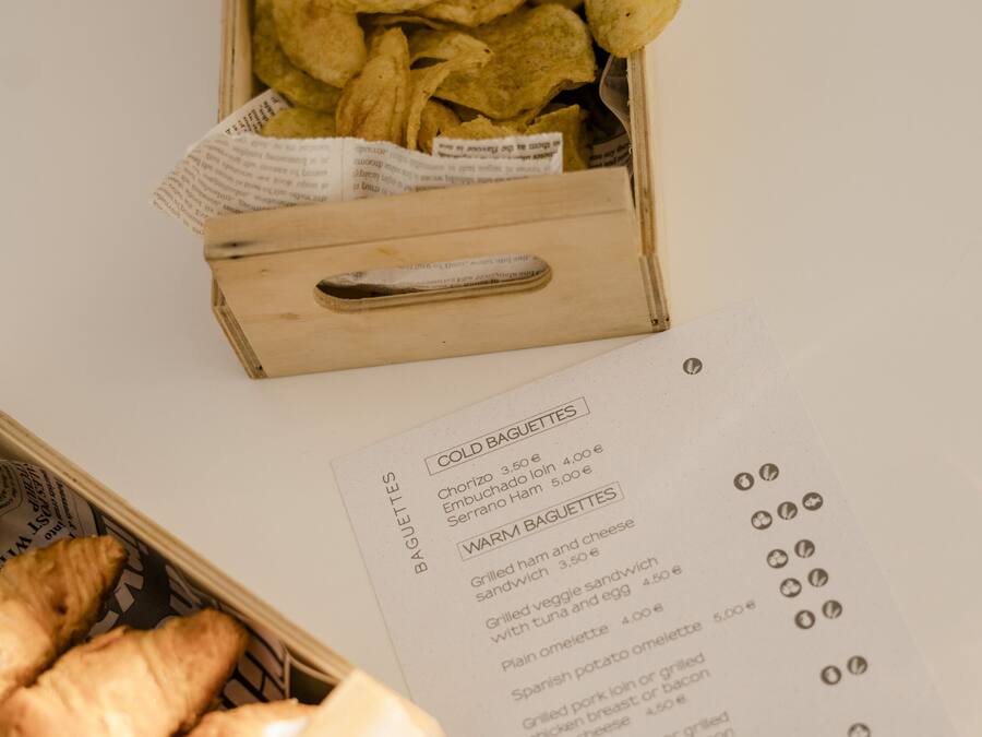 Eine Tüte Chips, eine Speisekarte und ein Korb mit Croissants.