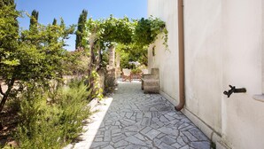 A narrow stone pathway leading to a white building with a door and a window. - Villa Teresa (Ugento)