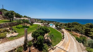 Una propiedad costera con un camino curvo, una piscina y vista al mar.